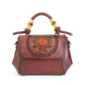 Vintage leather crossbody handbag with bamboo handle and embossed floral flap design. - Coffee