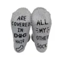 Close-up detail of fluffy grey fuzzy novelty socks featuring funny non-slip letter soles. - Gray