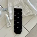 Black mid-tube socks featuring white bow patterns and lettuce edge, sweet ballet style. - One Size / Black