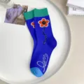 Chaussettes bleues mi-hautes avec un motif de fleur souriante et des bords côtelés verts. - CX380 une fleur