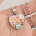 Hart glas hanger ketting met een fijn vlinder en bloem motief detailopname dichtbij. - Roze Vlinder / Inclusief 60cm Ketting