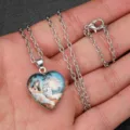 Detailed close-up of a silver-tone chain necklace with a heart-shaped glass pendant showing fantasy art. - Girl and Grey Wolf Style (AA334)