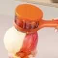Orange handheld fruit peeler with storage container for apples, pears and asparagus. - Orange