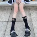 Detailed view of women's black sheer lace ruffle mid-tube socks paired with crystal mary janes. - One Size / Black Ankle Socks