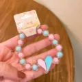 Detailed close-up view of the colorful beaded bracelet with a cute heart charm and tag. - Two-Tone Heart