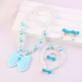 Close-up of children jewelry set featuring blue bow pendants and white pearls, detail view. - Bow Set (Transparent Bag) / Light Blue