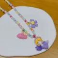Close-up detail of colorful beaded necklace with cute resin cartoon princess pendant. - Bag Packaging / Purple Angel