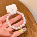 Detailed close-up of faux pearl beaded bracelet featuring a colorful star pendant. - Shooting Star