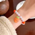 Kids cute pearl bracelet with carrot pendant, children wrist jewelry main display photo. - Carrot