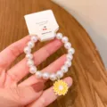 Cute pearl bracelet with yellow daisy charm, elegant style student jewelry detail view. - Daisy