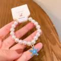 Detailed view of the cute pearl bracelet with blue starfish pendant charm closeup shot. - Blue Starfish