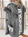 Detailansicht des grauen oversize Kapuzen-Strickjacke mit auffälligem Buchstabenmuster. - S / Grau
