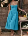Detailed view of the elegant blue bustier midi dress in a charming rustic outdoor scene. - Lake Blue
