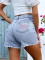 Women's light blue stretch denim shorts featuring pink bow embroidery and stylish frayed raw hems. - XXS / Bottoms / Blue