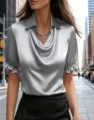 Detail shot of a silver satin cowl neck short sleeve blouse with ruffled cuffs on street. - Gray