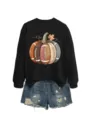 Detailed view of the black sweatshirt featuring a unique football pumpkin graphic print. - S / Tops / Black