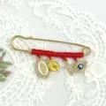 Detailed view of the red braided rhinestone brooch featuring evil eye and cross charms. - Style 2