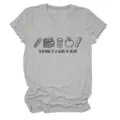 Gros plan sur l'imprimé graphique et la texture douce du tissu de ce t-shirt décontracté. - S / Hauts / Gris Clair (Graphisme couleur avec texte noir)