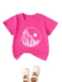 Rosa Kinder T-Shirt mit kurzen Ärmeln, Bergmotiv Aufdruck und weißen Babyschuhen als Deko. - 90 / Oberteile / Fuchsia