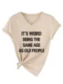 Λεπτομερής όψη μπεζ t-shirt με V λαιμόκοψη κοντομάνικο με σλόγκαν και κόμπο στο στρίφωμα. - S / Tops / Χρώμα της Άμμου