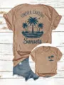 Nahaufnahme Detail des lässigen Damen Kurzarm T-Shirts mit Sonnenuntergang Palmen Grafik. - Hellkaffee