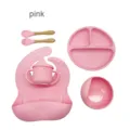 Pink baby silicone tableware set including divided plate, bowl, cup, bib, and wooden utensils. - Pink