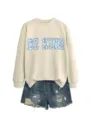 Vista di dettaglio di felpa beige casual con stampa floreale blu e pantaloncini di jeans. - Taglia S / Top / Colore sabbia