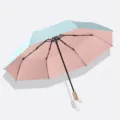 Kompakter 3-fach Sonnenschirm mit hellblauem Außenmaterial und rosa Innenseite, 8 Rippen. - 3-fach faltbarer manueller Regenschirm mit 8 Streben, Holzgriff und Farbbeschichtung in Himmelblau