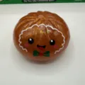 Close up of glitter brown Christmas bun squishy toy with cute face and bow, stress relief. - 8.5cm / Gingerbread Man