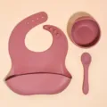 Silicone baby feeding set detail, featuring a soft bib, bowl, and spoon in dusty pink. - Mother & Baby 3-Piece Set (Brick Red)