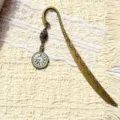 Vintage bronze metal bookmark with clock pendant and carved scroll patterns for book lovers. - Finished Product as Shown