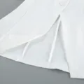 Close up view of the white blazer detail showcasing the elegant hem, slit and button design. - S / Tops / White