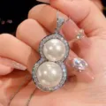 Close-up detail of a double-pearl gourd pendant necklace with sparkling zircon pavé setting. - Platinum White Pearl Pendant with Box Chain