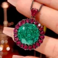 Close-up detail of luxury black gold pendant necklace with green geometric center stone and red gems. - Pendant With Necklace