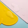 Silicone cloud placemat detail view, waterproof baby dining mat in bright yellow and pink colors. - Orange