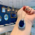 Stunning pear-shaped dark blue gemstone pendant necklace with shimmering crystal halo setting. - Blue Glass Pendant