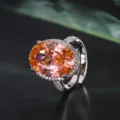 Superbe gros plan d'une grande bague en pierre précieuse orange ovale avec des détails pavés. - Bague Padparadscha Taille Nid d'Oiseau