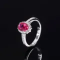Gros plan détaillé de la superbe bague avec pierre rouge ovale et halo de zircones scintillantes. - Style Corindon Rouge