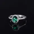 Détail de bague élégante avec pierre précieuse verte et halo de zircons scintillants. - Style Nano Vert