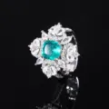 Primer plano detallado de un elegante anillo con piedra preciosa verde y circonitas brillantes. - Anillo de Esmeralda