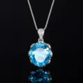 Close-up detail of a sparkling oval blue gemstone pendant necklace with delicate pavé bale. - Aquamarine Blue Pendant With Chain