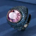 Close-up of a bold black gold ring with an oval pink center stone and blue crystal pavé details. - Oval Main Stone (ZS1149 Black Gold) / Black Gold Pink