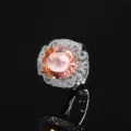 Primo piano dettagliato di un lussuoso anello cocktail con gemma arancione e montatura scintillante. - Anello Padparadscha Taglio a Nido d'Uccello