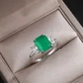 Scatto di dettaglio di un elegante anello a tre pietre con pietra verde taglio smeraldo. - Taglia 6 / Verde