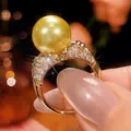 Primo piano dettagliato dell'anello con perla dorata e pietre scintillanti ed eleganti. - Anello con Perla Dorata / Taglia 6