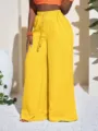 Close-up details of the yellow textured wide-leg pants showing the high waist and drawstring. - Yellow