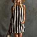 Detailed view of the black and white vertical striped linen sleeveless mini dress worn by model. - Black and White