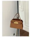 Brown suede texture handbag detail shot, featuring metallic turn-lock closure and elegant strap. - Brown
