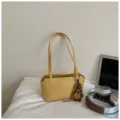 Minimalistische einfarbige gelbe Schultertasche mit Blumenanhänger für den Alltag und Pendeln. - Mit Anhänger / Gelb