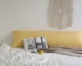 Détail de tissu doux oreiller long jaune dans une scène de chambre minimaliste confortable. - Jaune